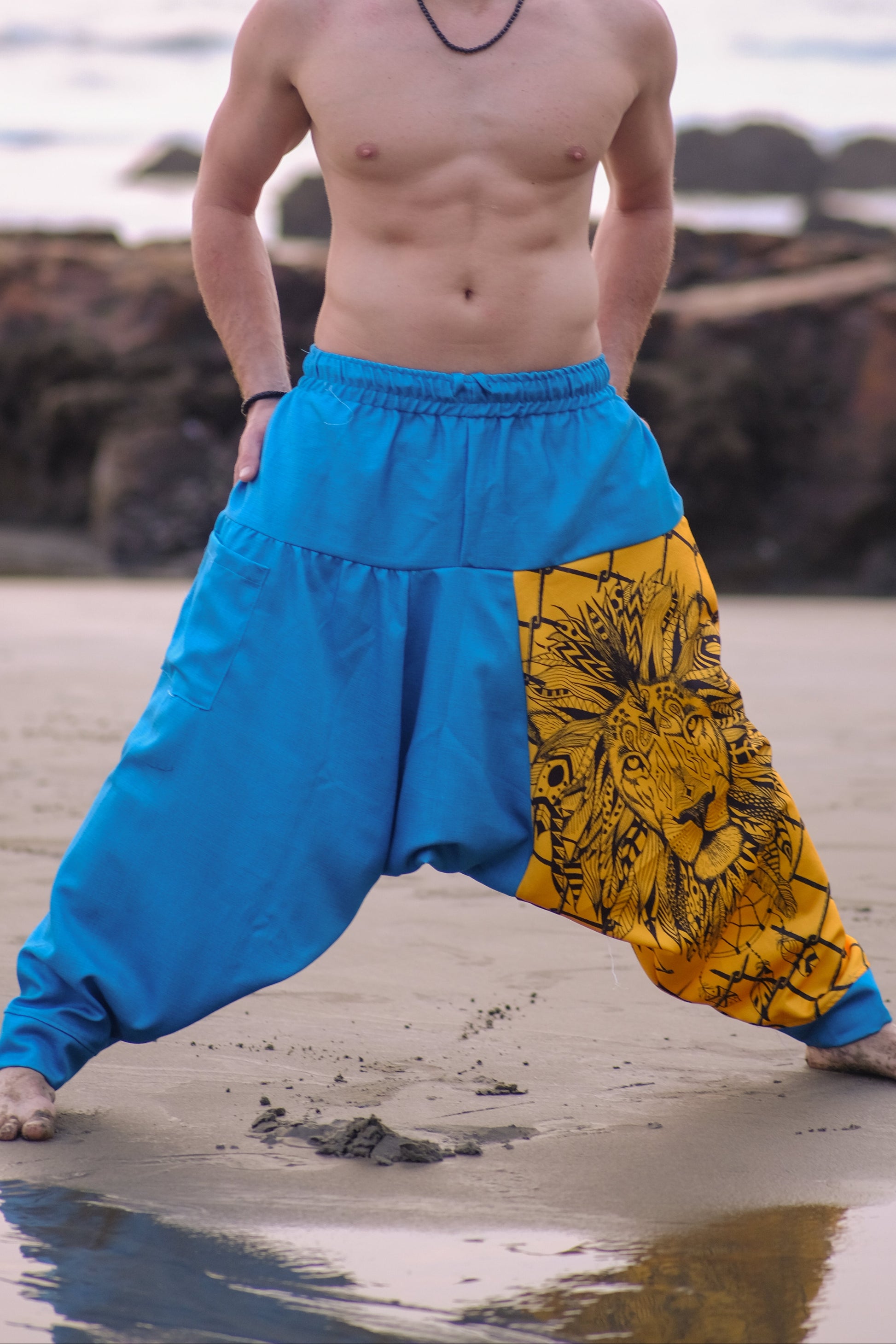 Man wearing blue and yellow harem pants on a beach
