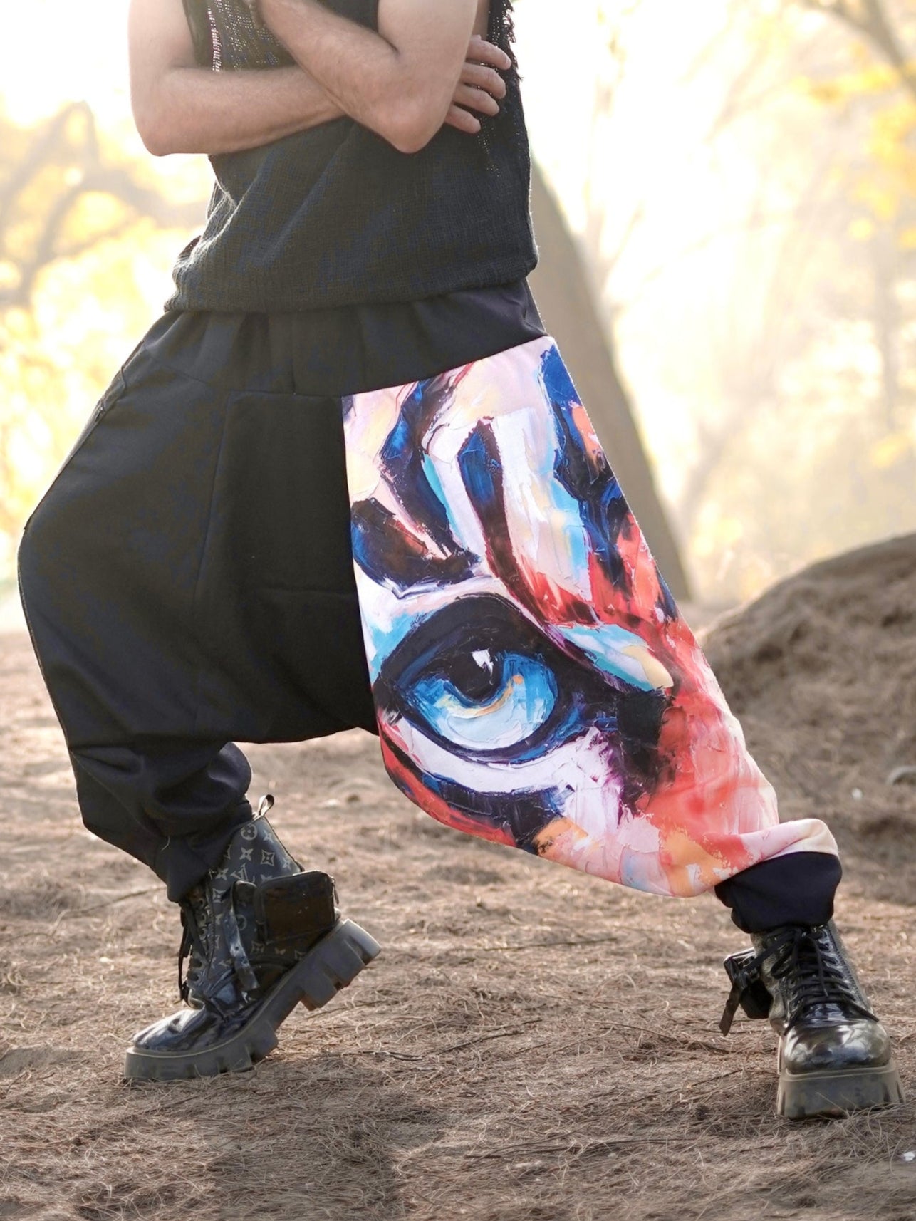 Person wearing a sleeveless top and colorful harem pants in a forest setting