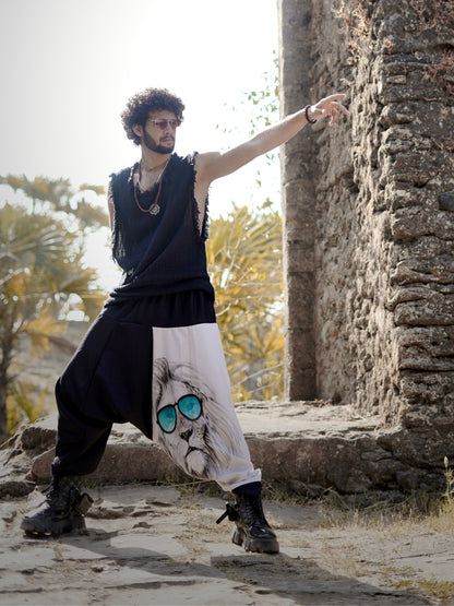 Man wearing a harem pants with a lion design, standing outdoors near stone ruins.