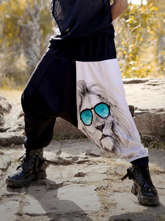 Man wearing a harem pants with a lion design, standing outdoors near stone ruins.