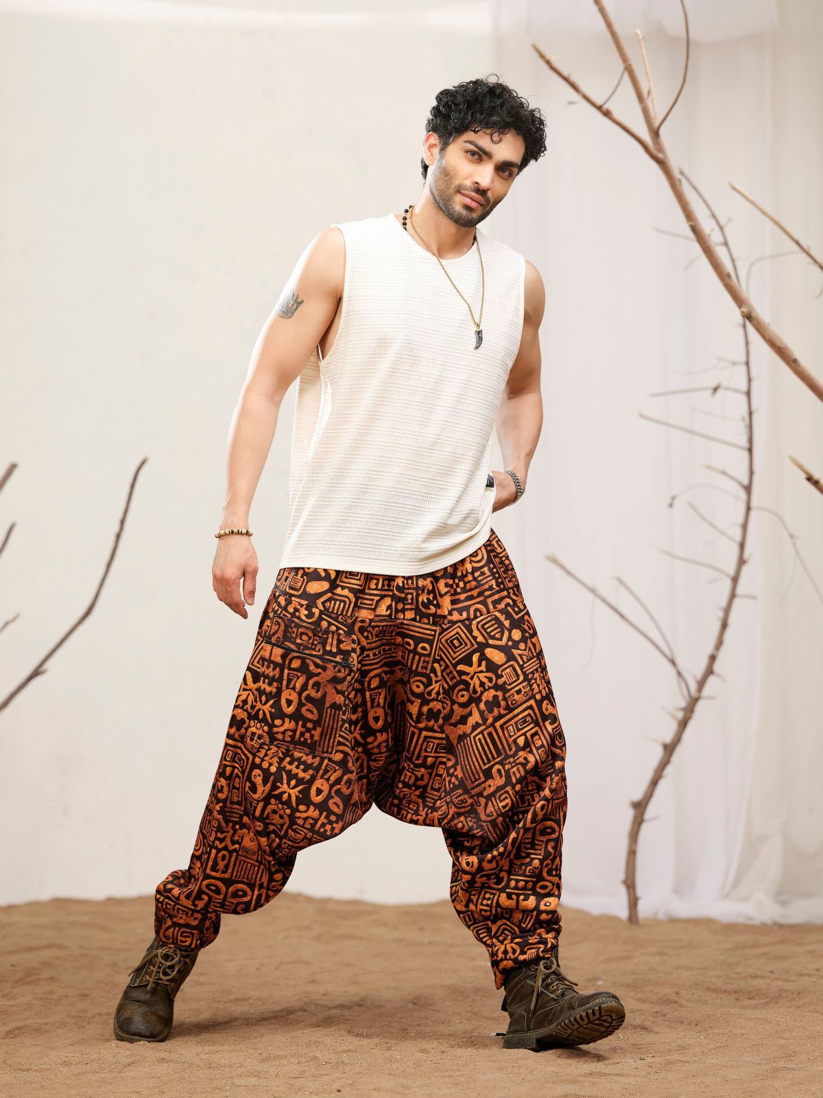 Rust-orange abstract glyph print on black harem pants for men